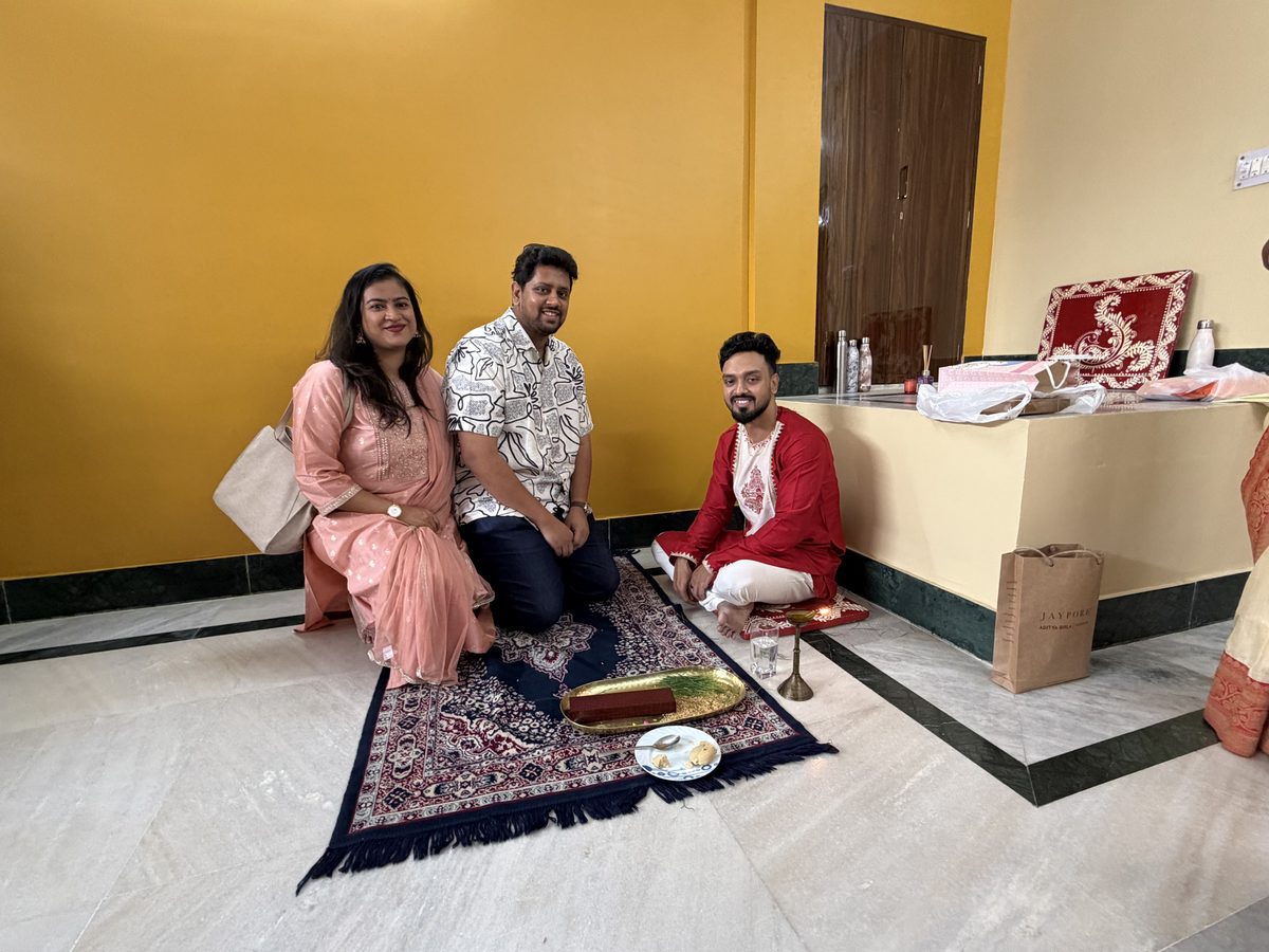 Family members seated together on the decorative prayer mat during ashirwad