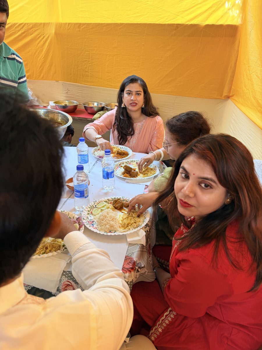 Family members gathered under a yellow tent eating together