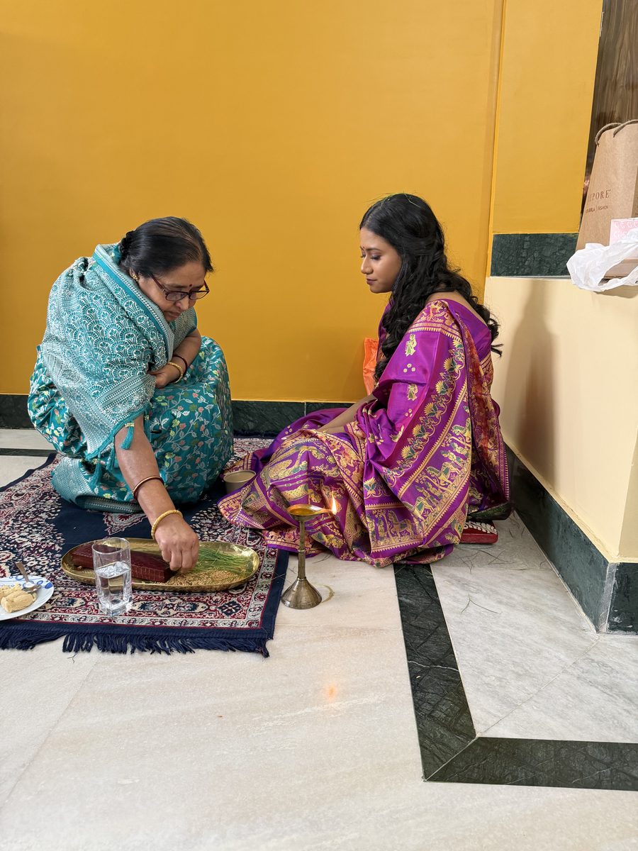 Woman in teal sari with Rituparna on the prayer mat during ashirwad