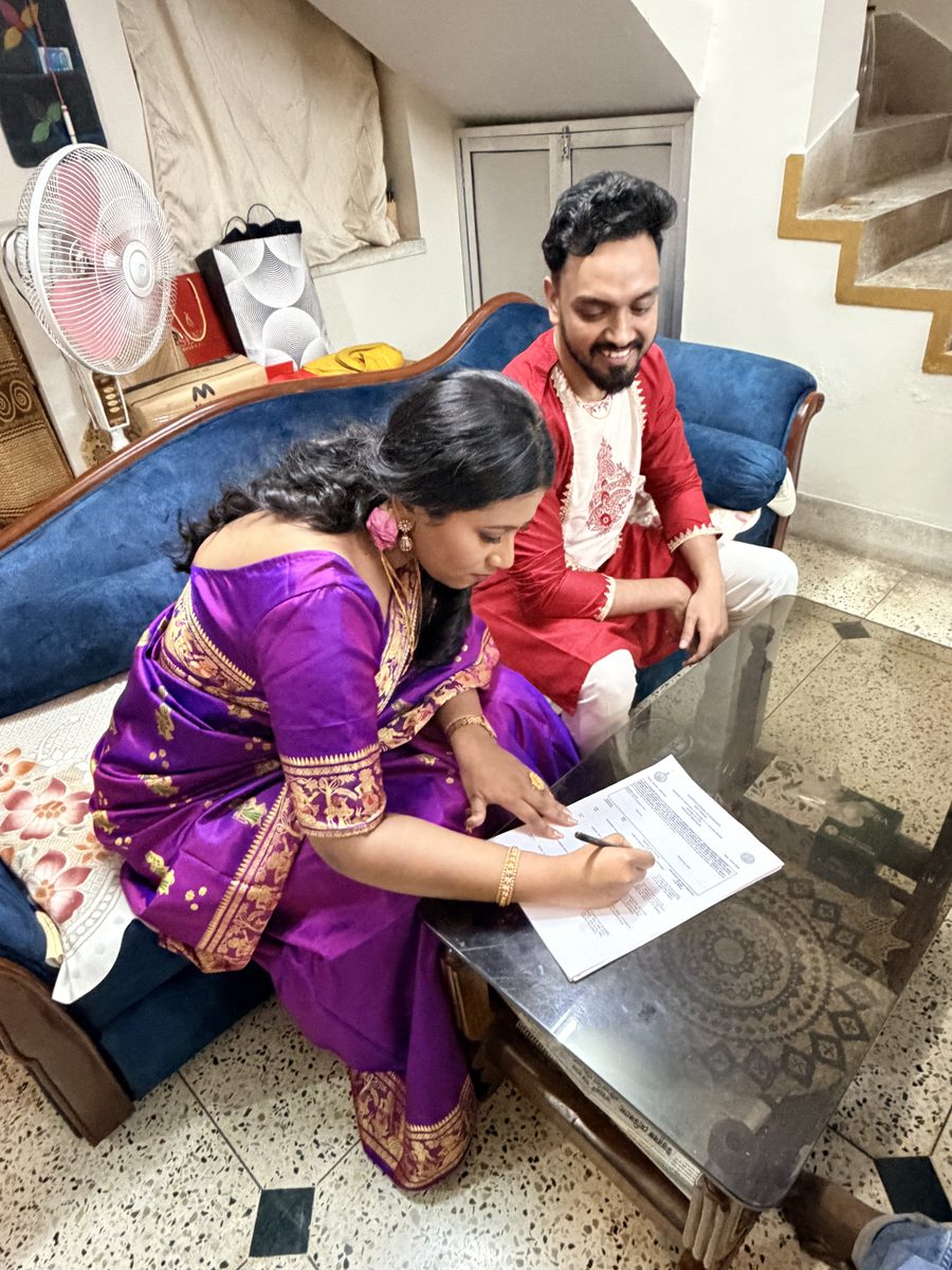 Rituparna in purple and Shoumo in red signing documents on the couch