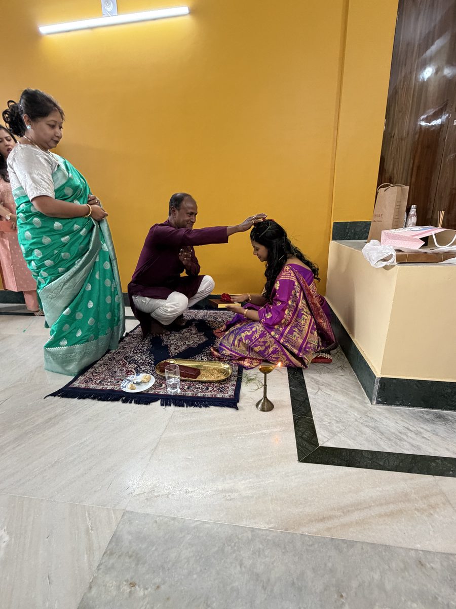 Man in maroon kurta blessing Rituparna with woman in green as witness