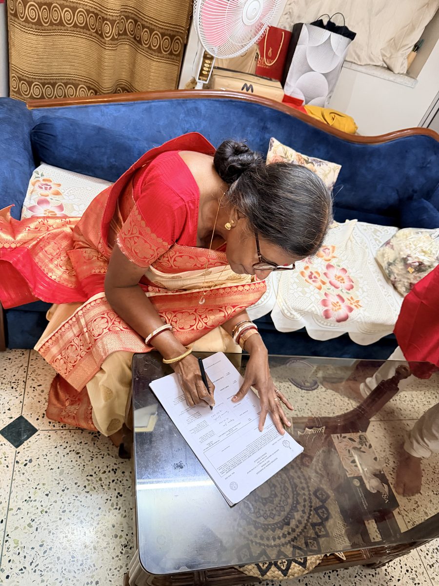 Woman in red sari carefully signing the ceremony documents