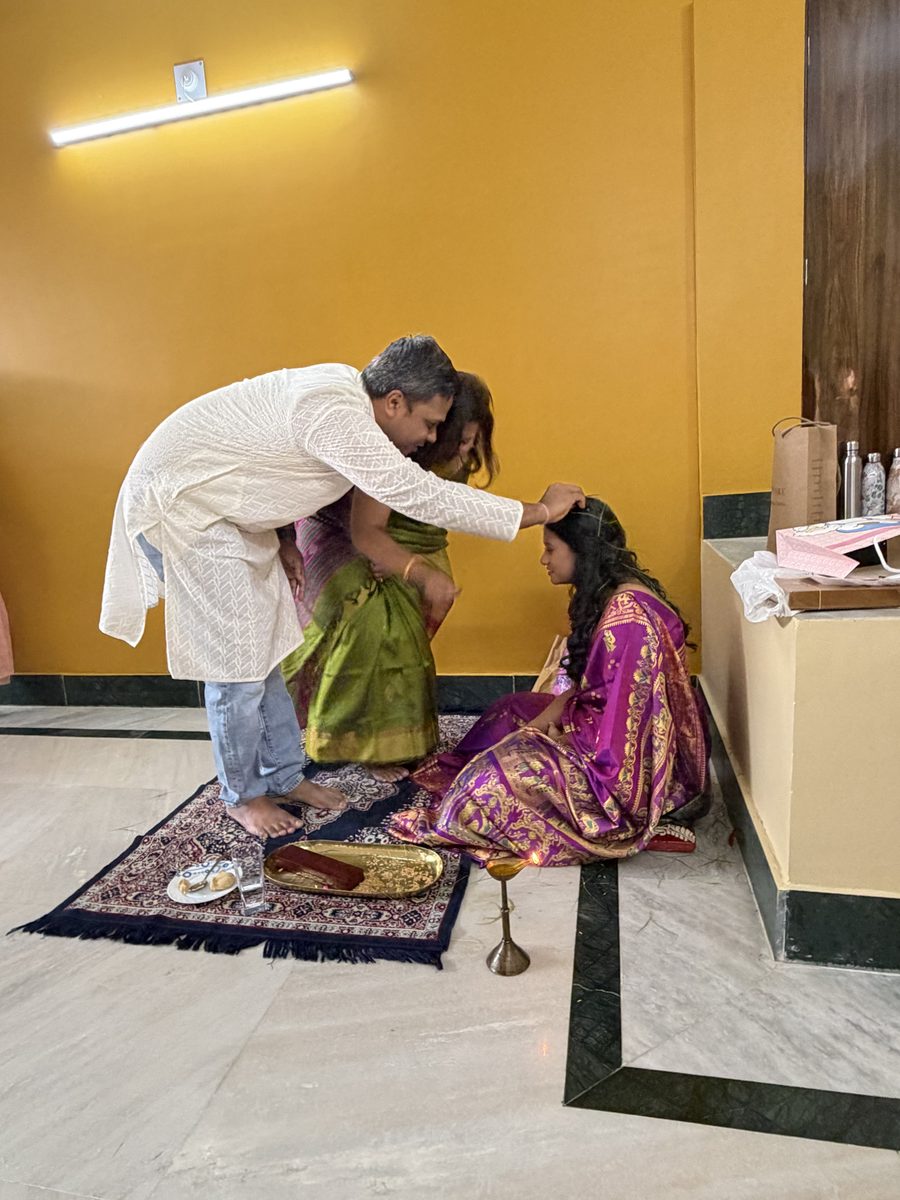 Man in white kurta blessing Rituparna on the prayer mat