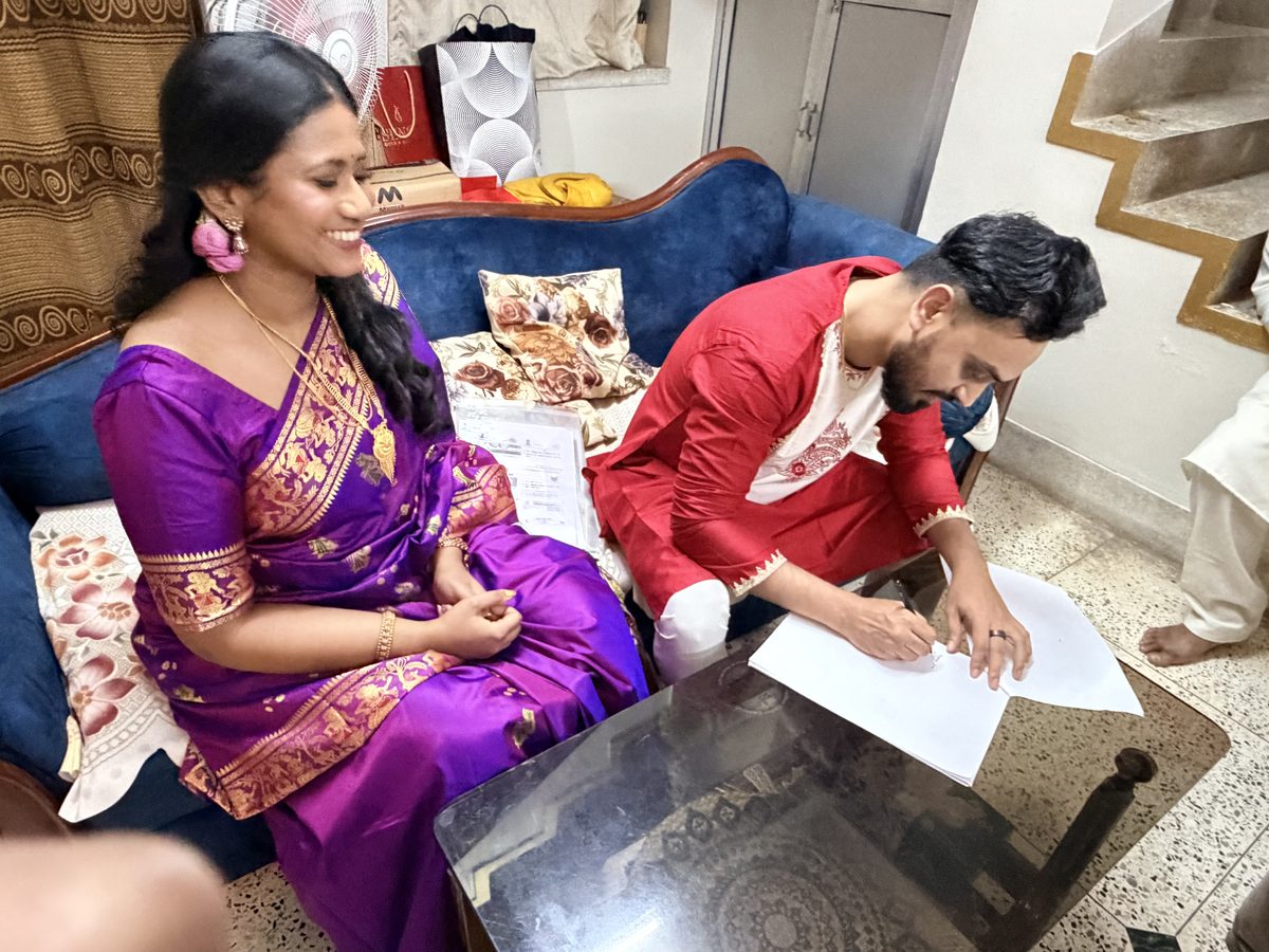 Rituparna and Shoumo casually signing documents on the couch