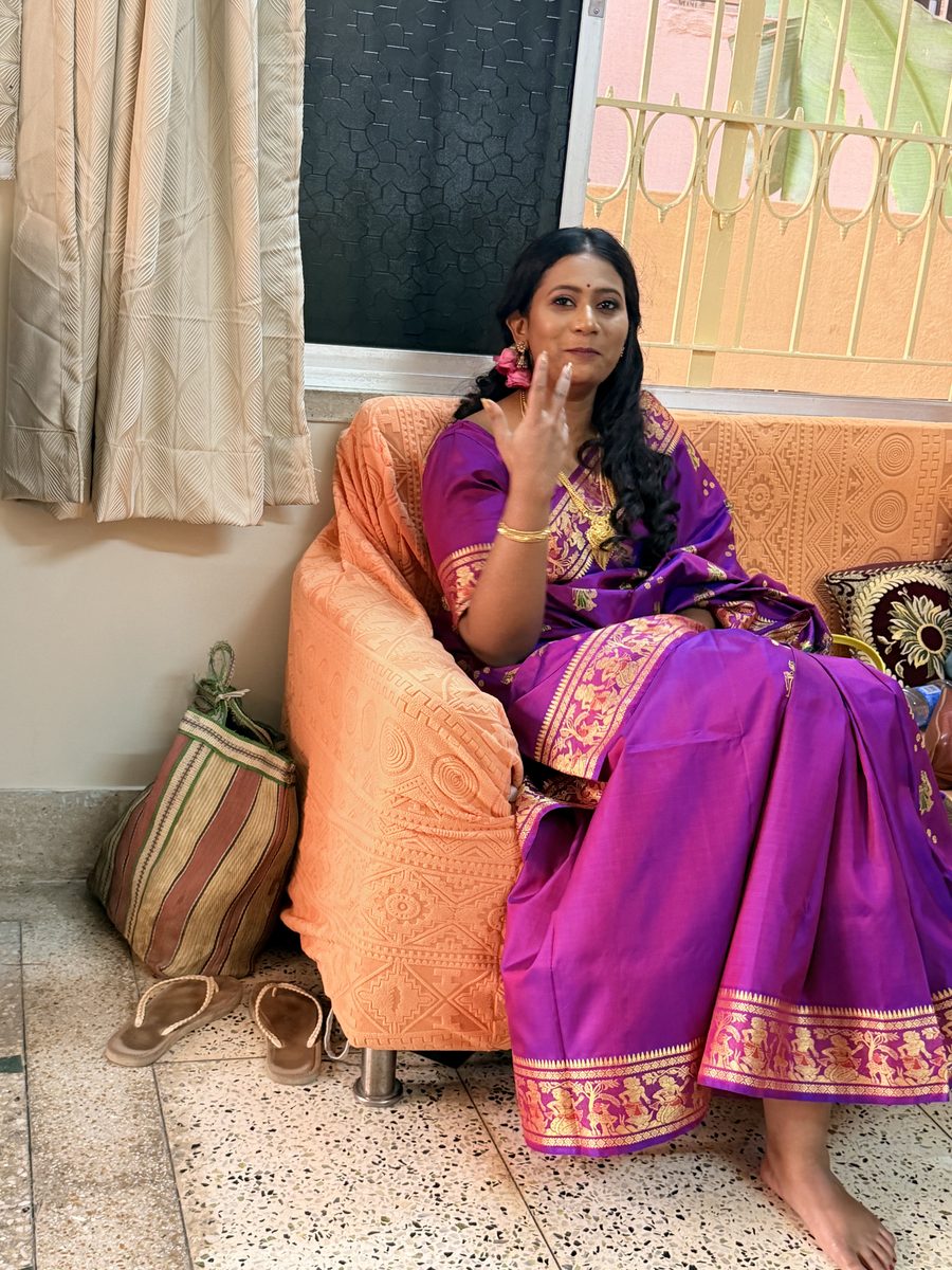 Rituparna sitting gracefully in her orange and purple Banarasi on the couch