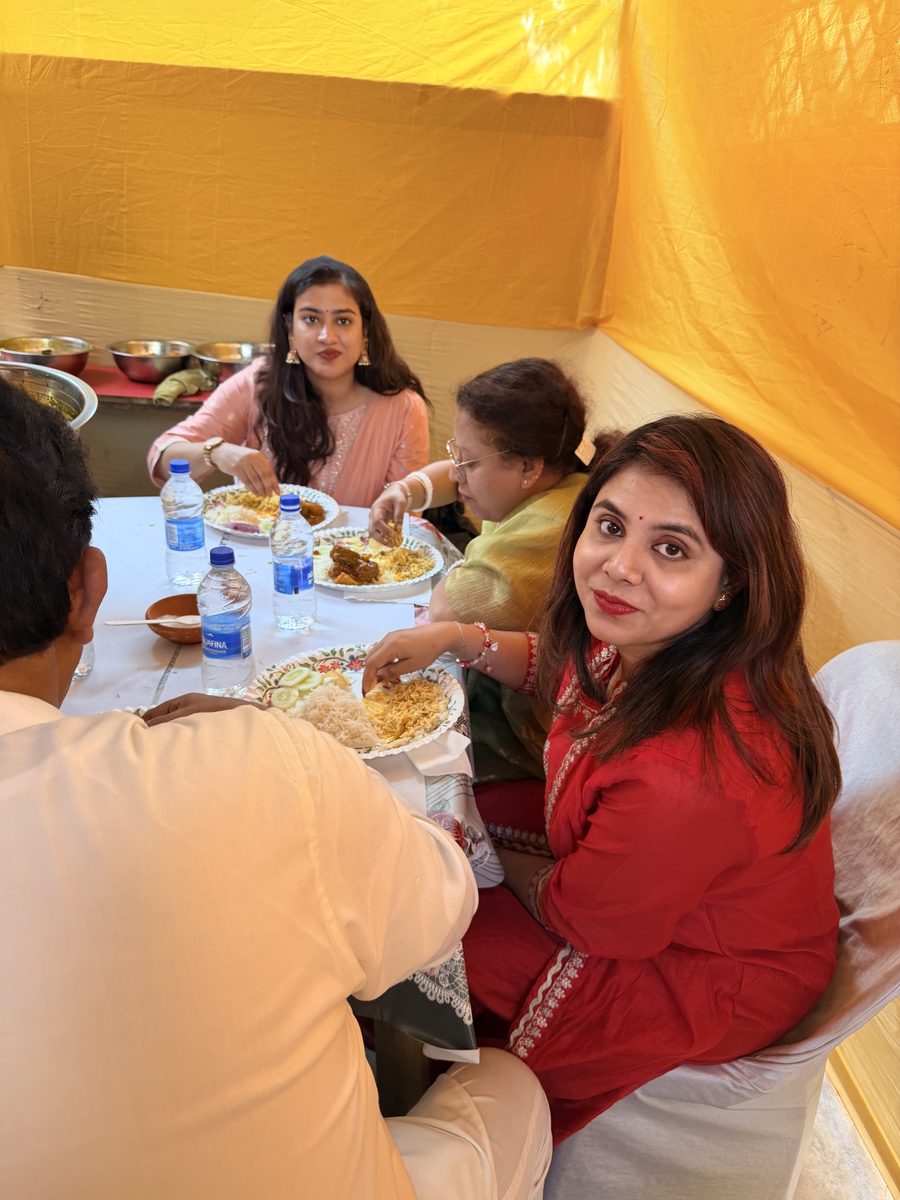 Women seated together eating under the tent at the celebration