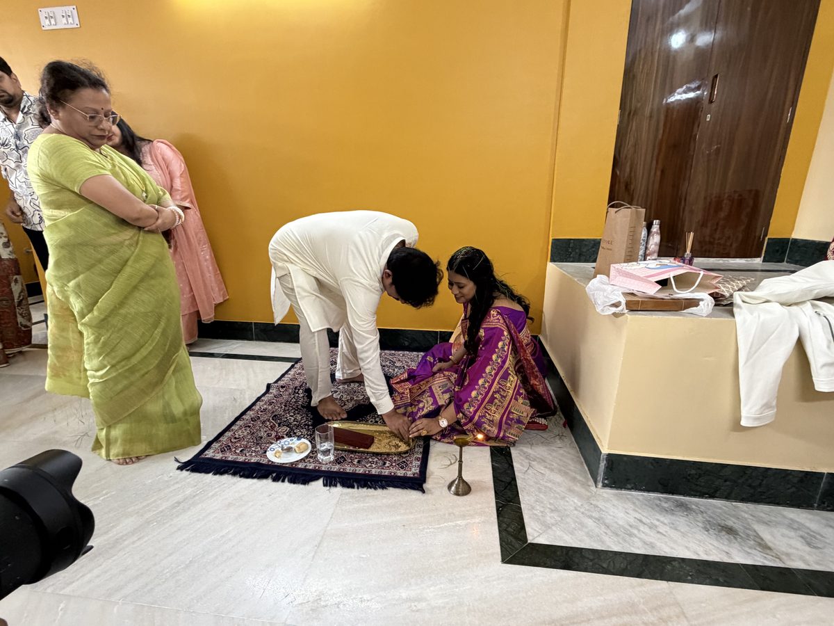 Elder man bending to bless Rituparna with family standing nearby