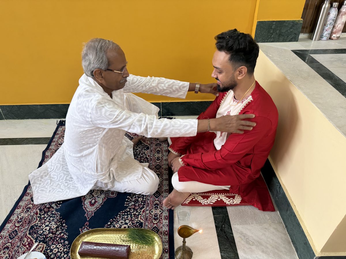 Elder man embracing and blessing Shoumo in his red kurta