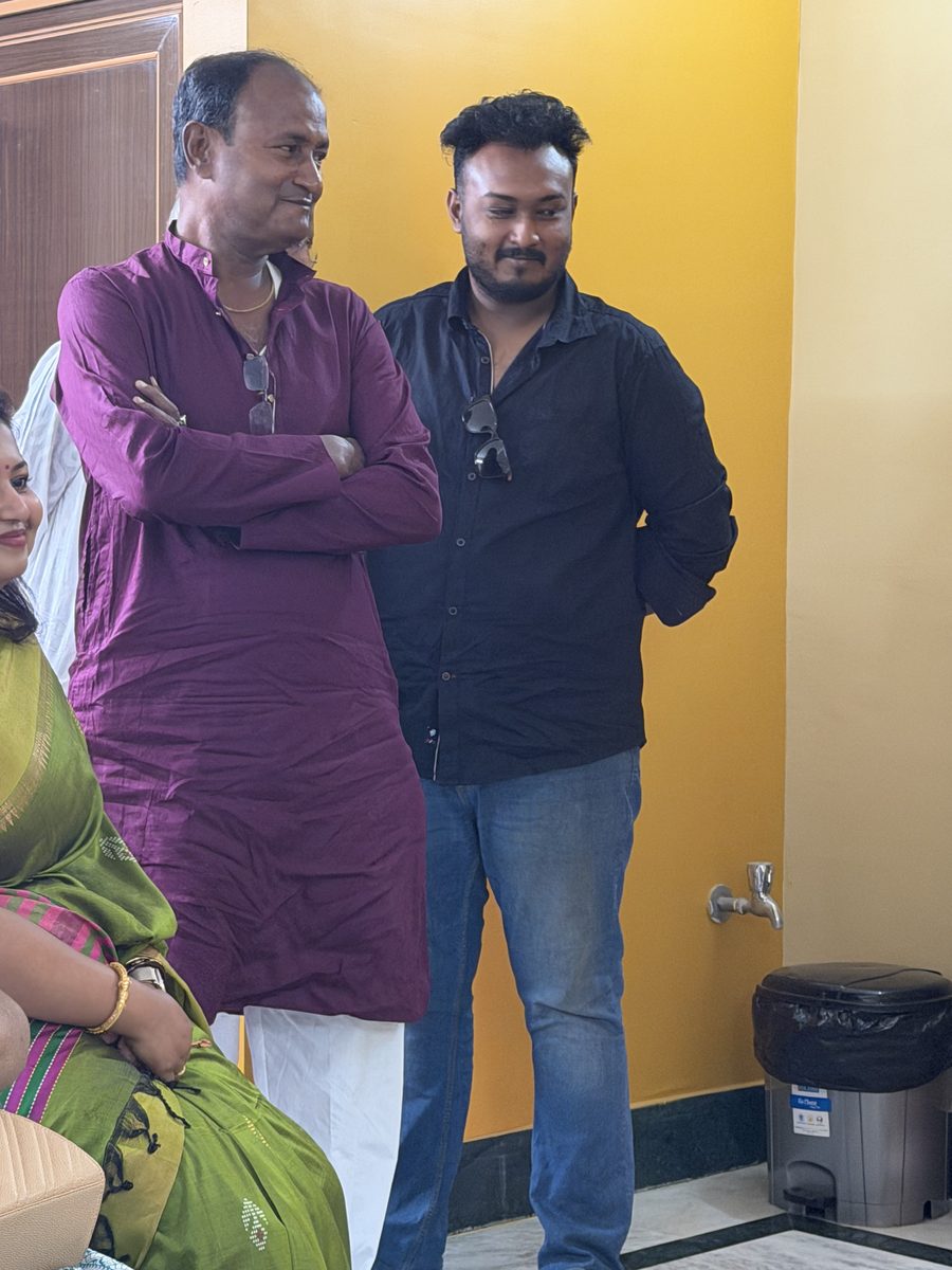 Elder man in maroon kurta and younger man in black standing together during the celebration