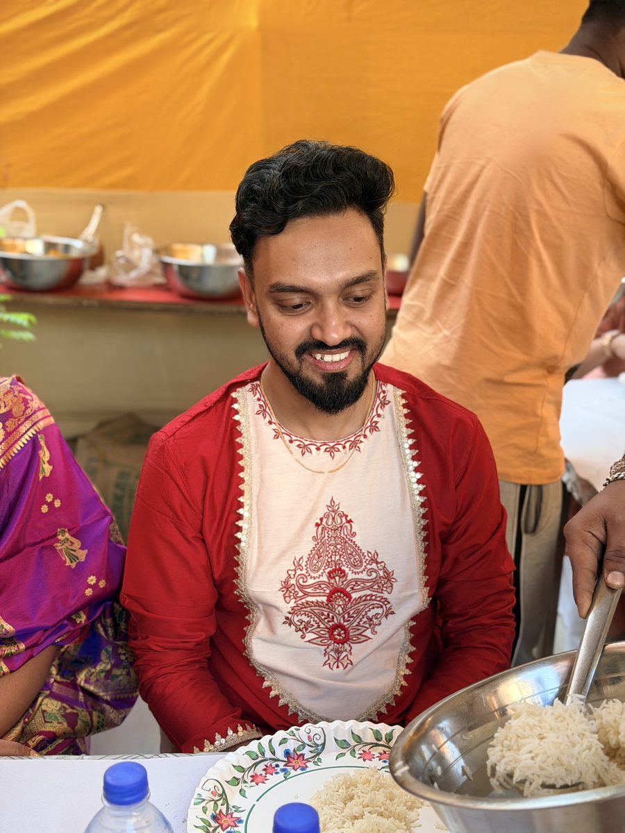 Shoumo smiling in his red kurta, surrounded by family at the celebration