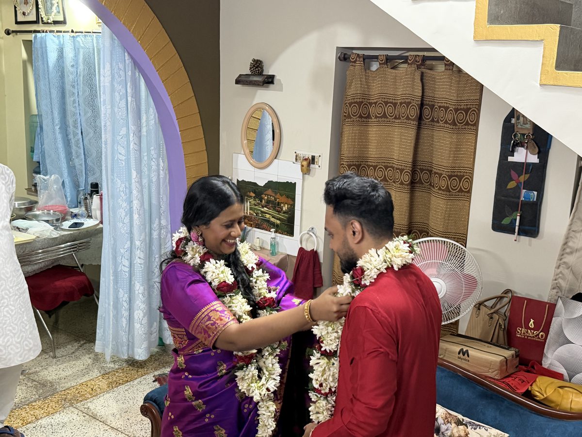 Rituparna tenderly touching Shoumo's forehead, both wearing garlands