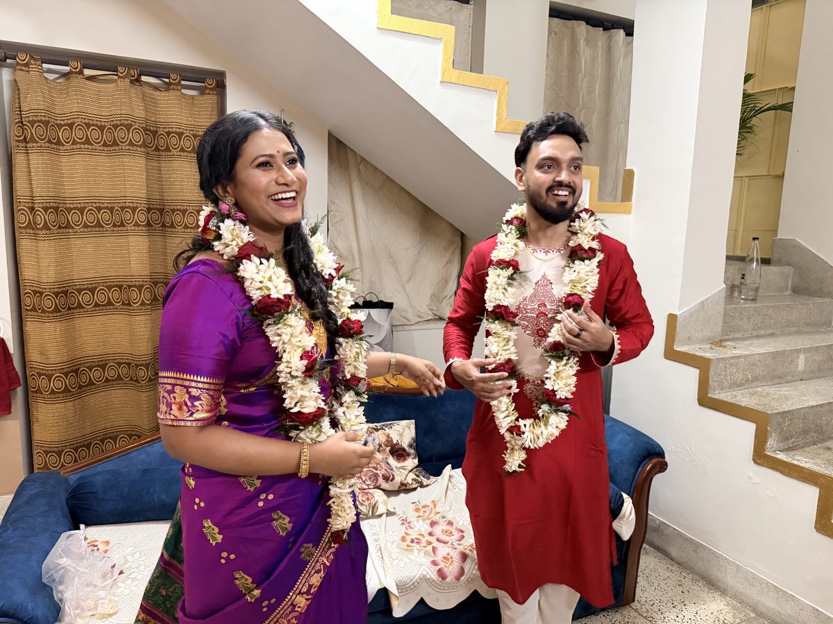 Rituparna and Shoumo seated together wearing garlands, smiling at camera