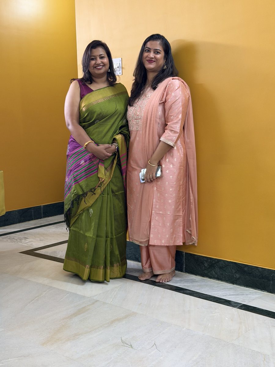 Two women standing elegantly in beautiful green and pink saris