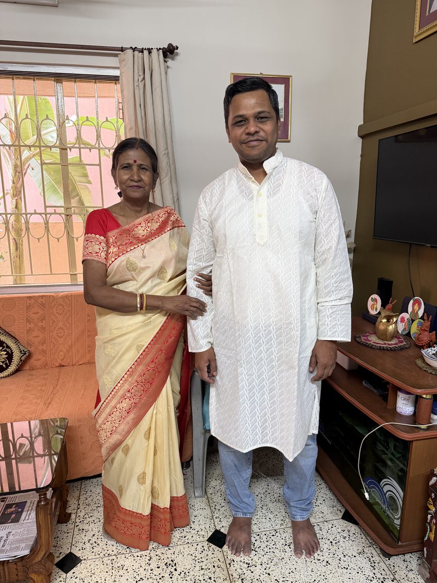 Man and woman in traditional cream attire posing together at home