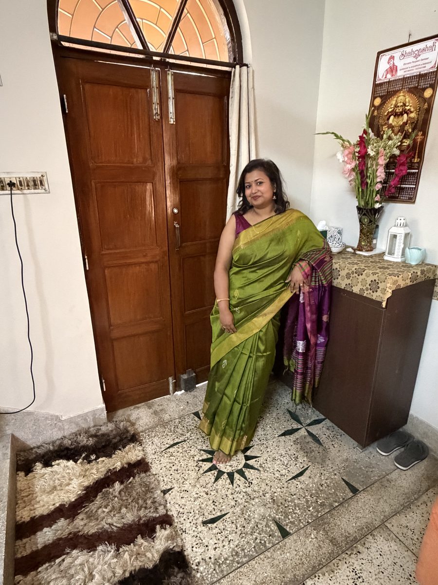 Woman in green and purple sari standing elegantly at the venue entrance