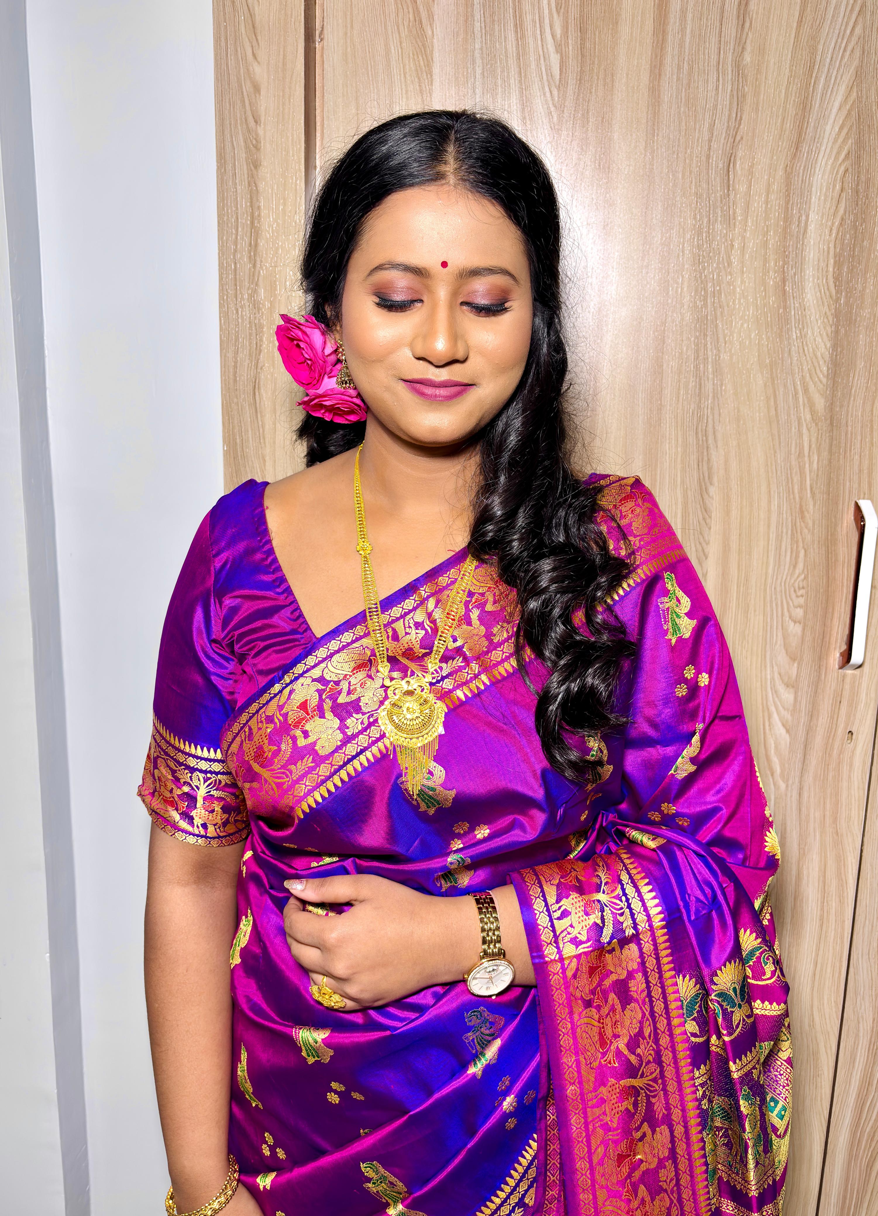 Rituparna looking down gracefully in her purple Banarasi with gold jewelry