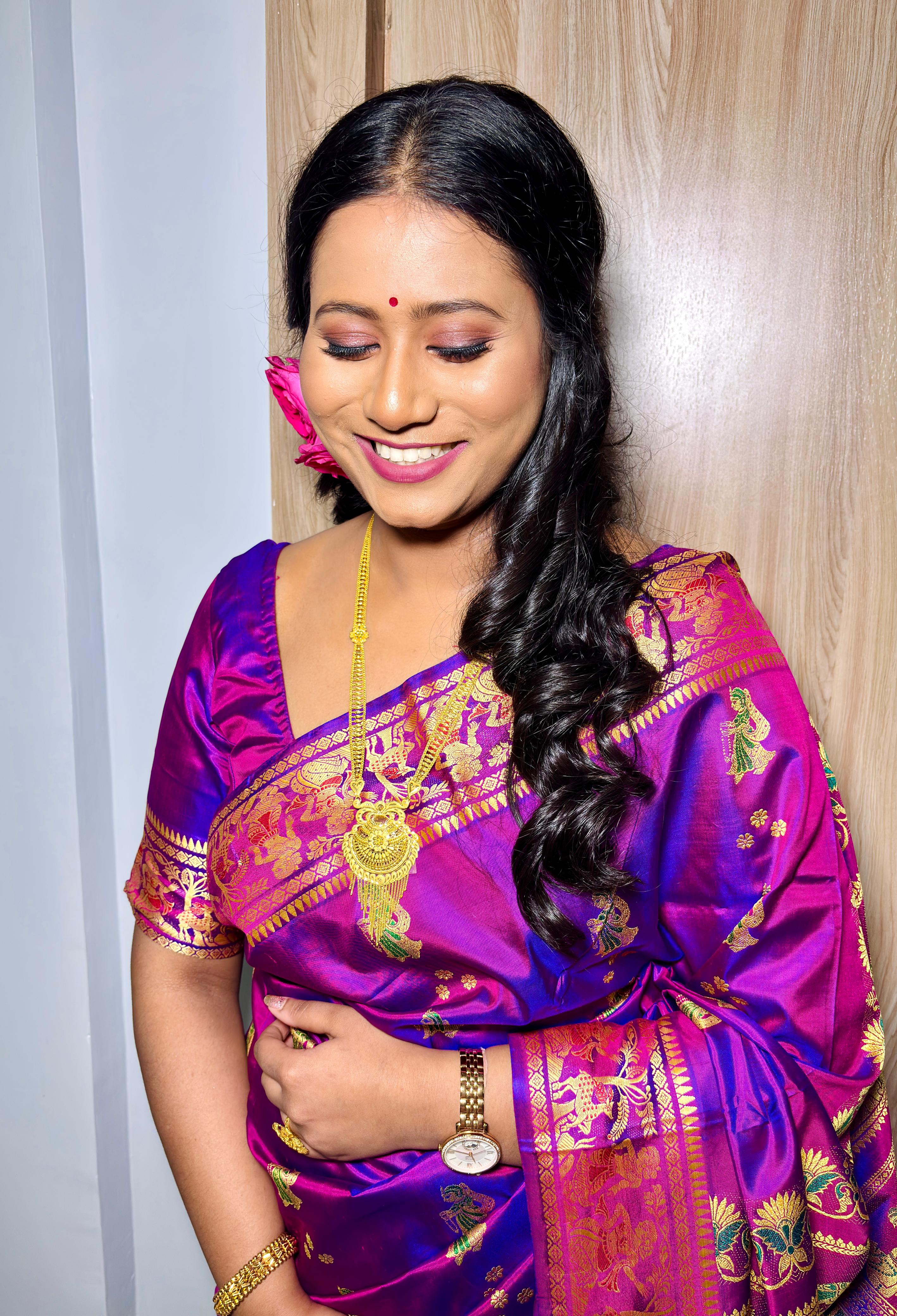 Rituparna smiling softly with eyes downcast, pink flower and gold necklace