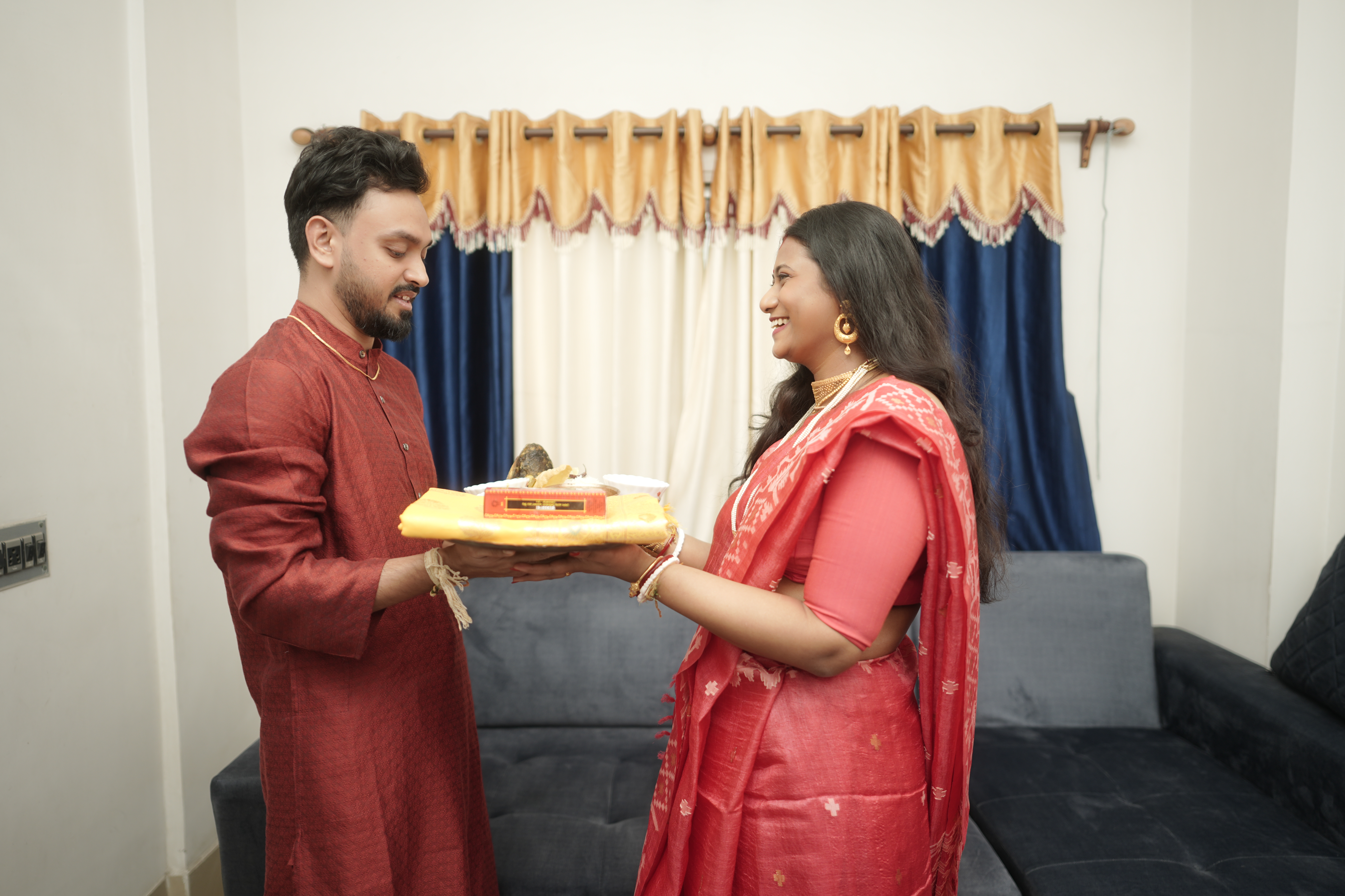 Shoumo presenting the sari and gifts to Rituparna, both exchanging warm smiles