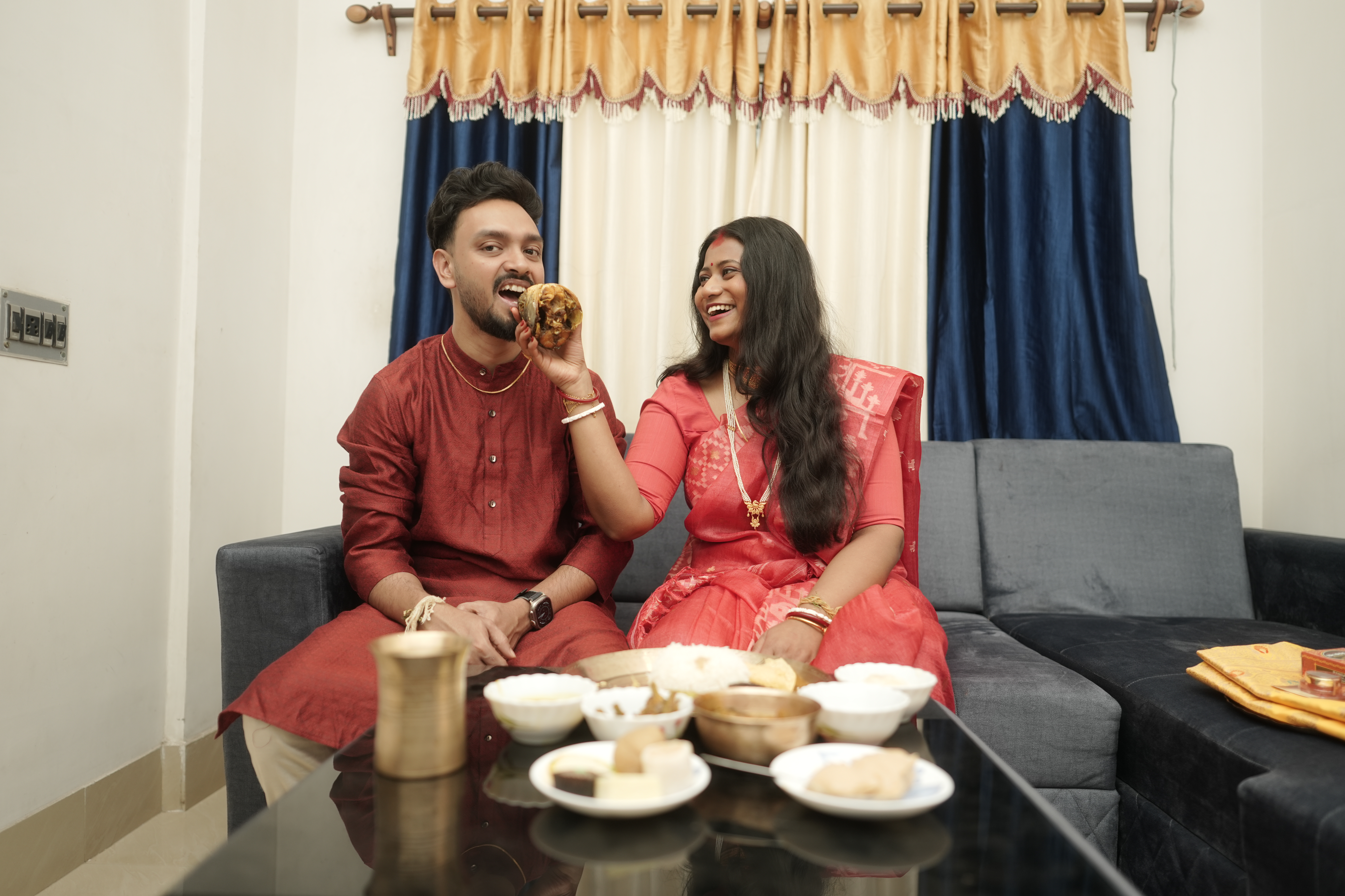 Rituparna playfully feeding Shoumo a piece of fish while both laugh