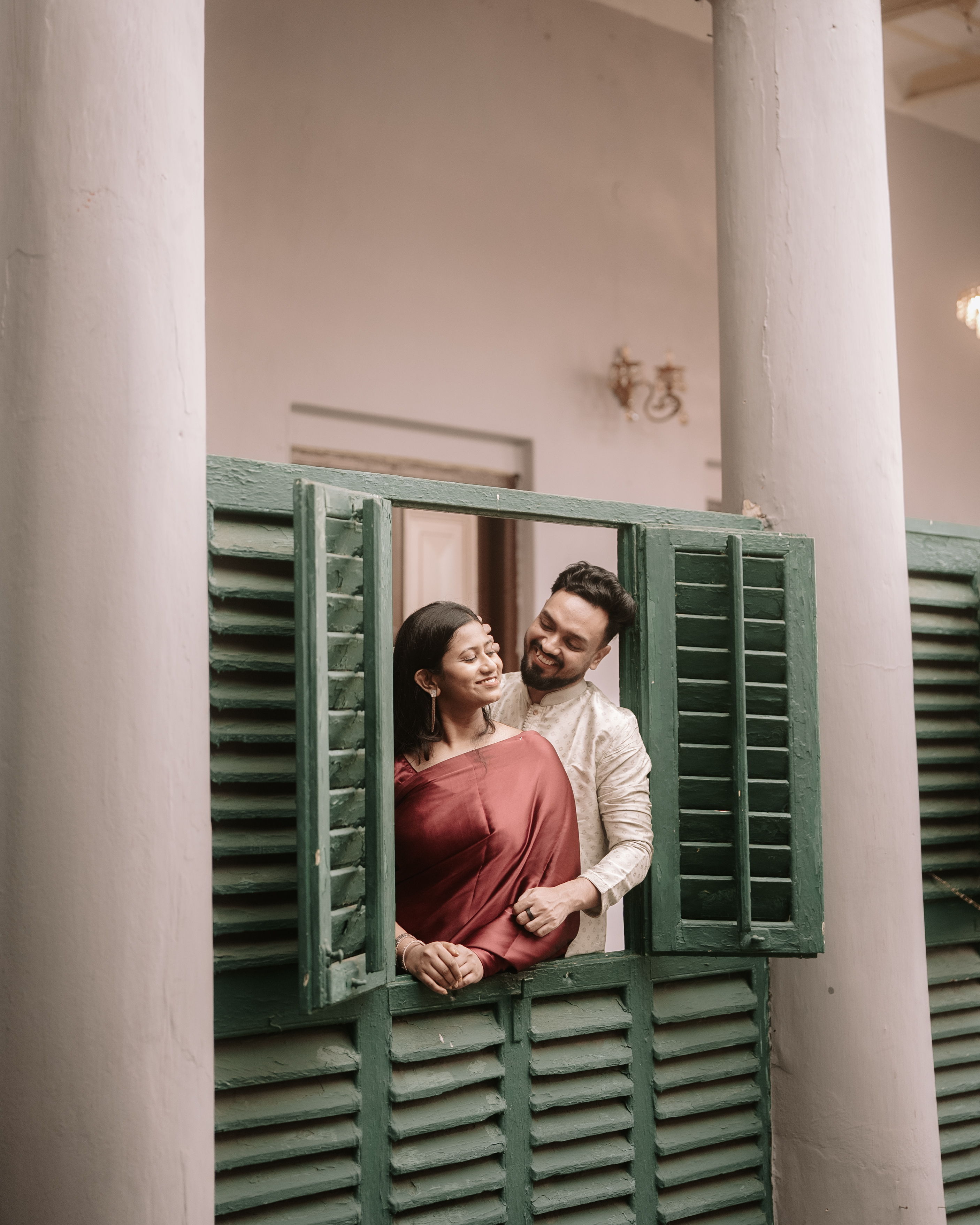 Portrait of Rituparna and Shoumo framed by green-shuttered windows of the haveli