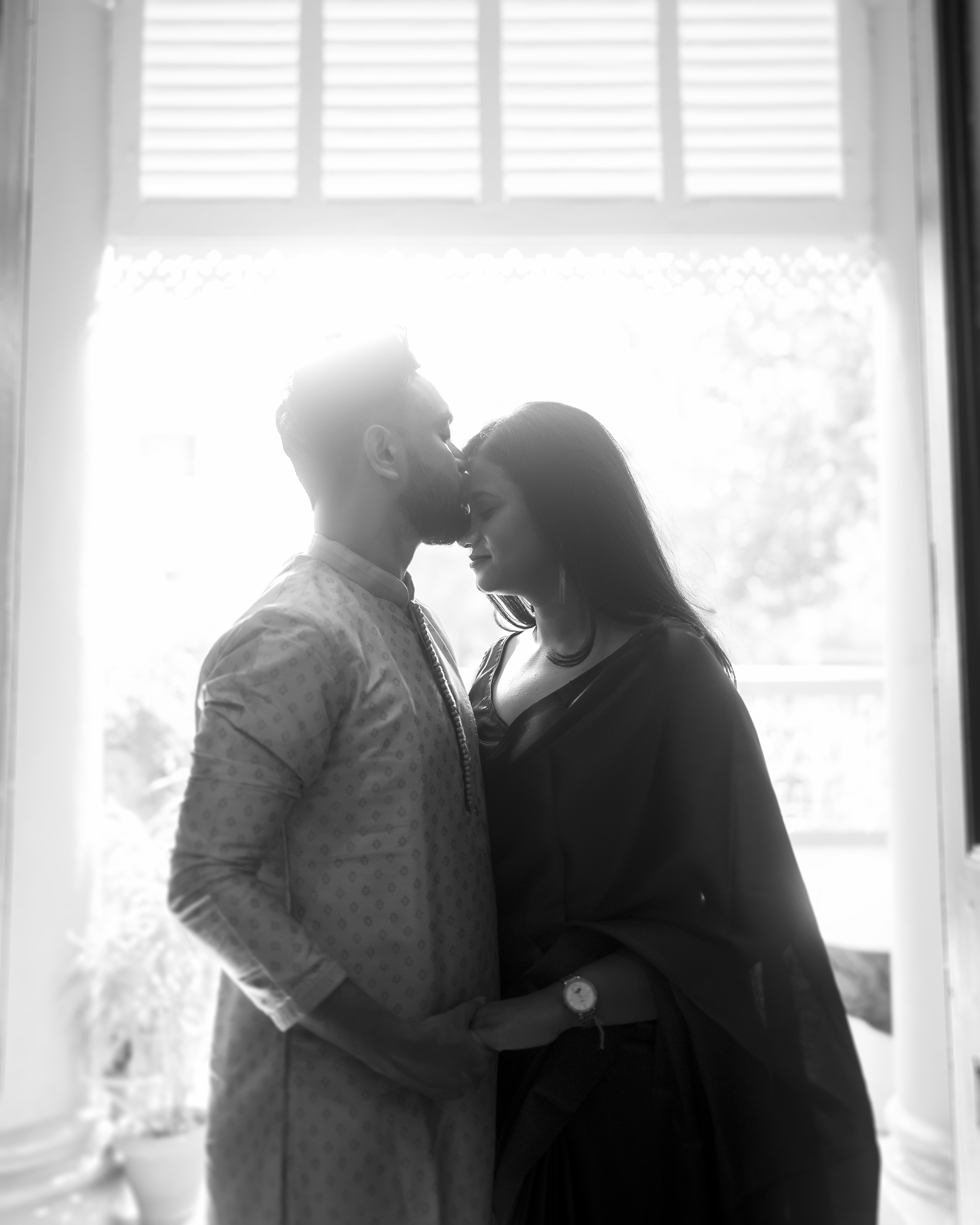 Window silhouette of the couple sharing a kiss, black and white