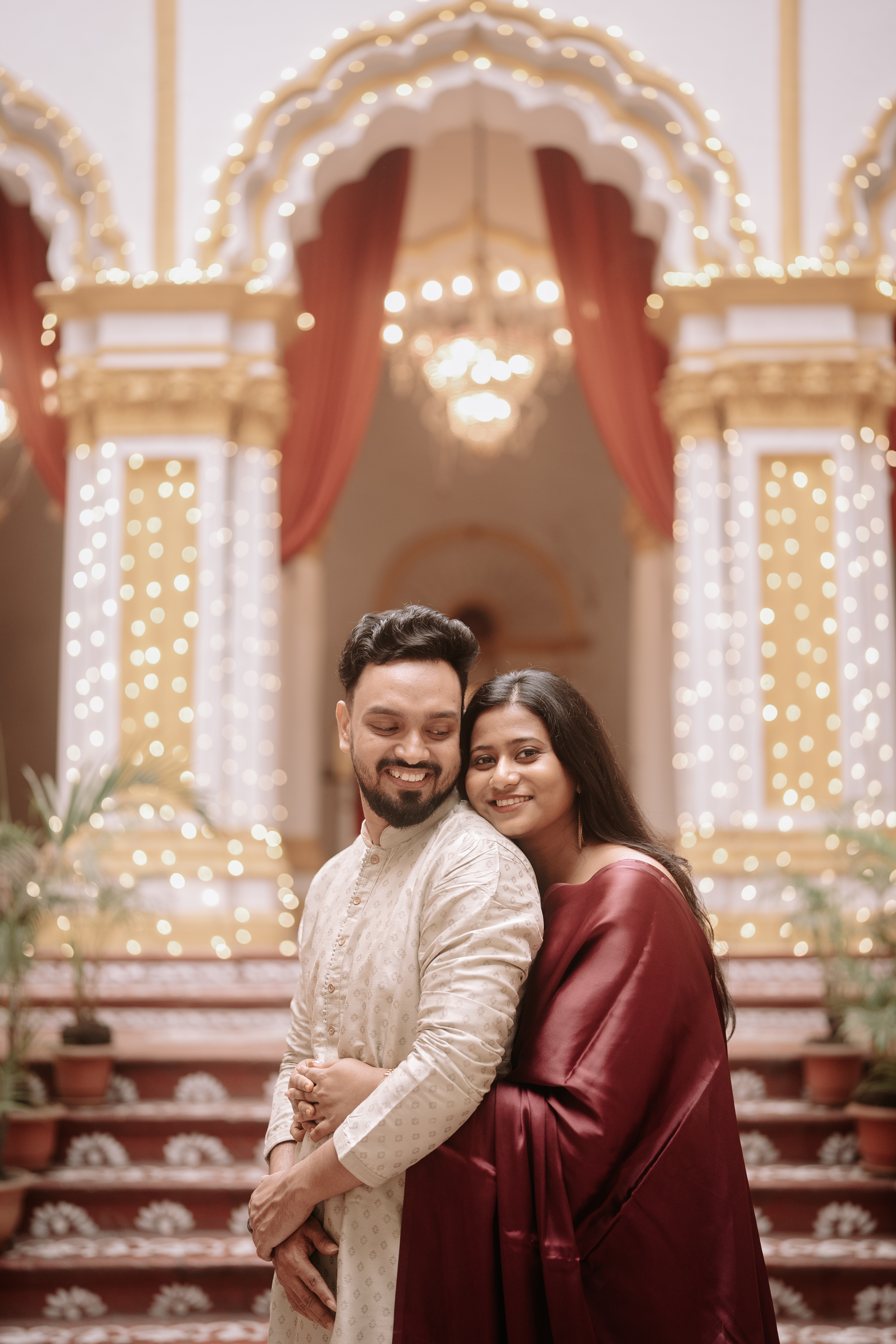 Wide shot of the opulent palace darbar hall with fairy lights and red drapes
