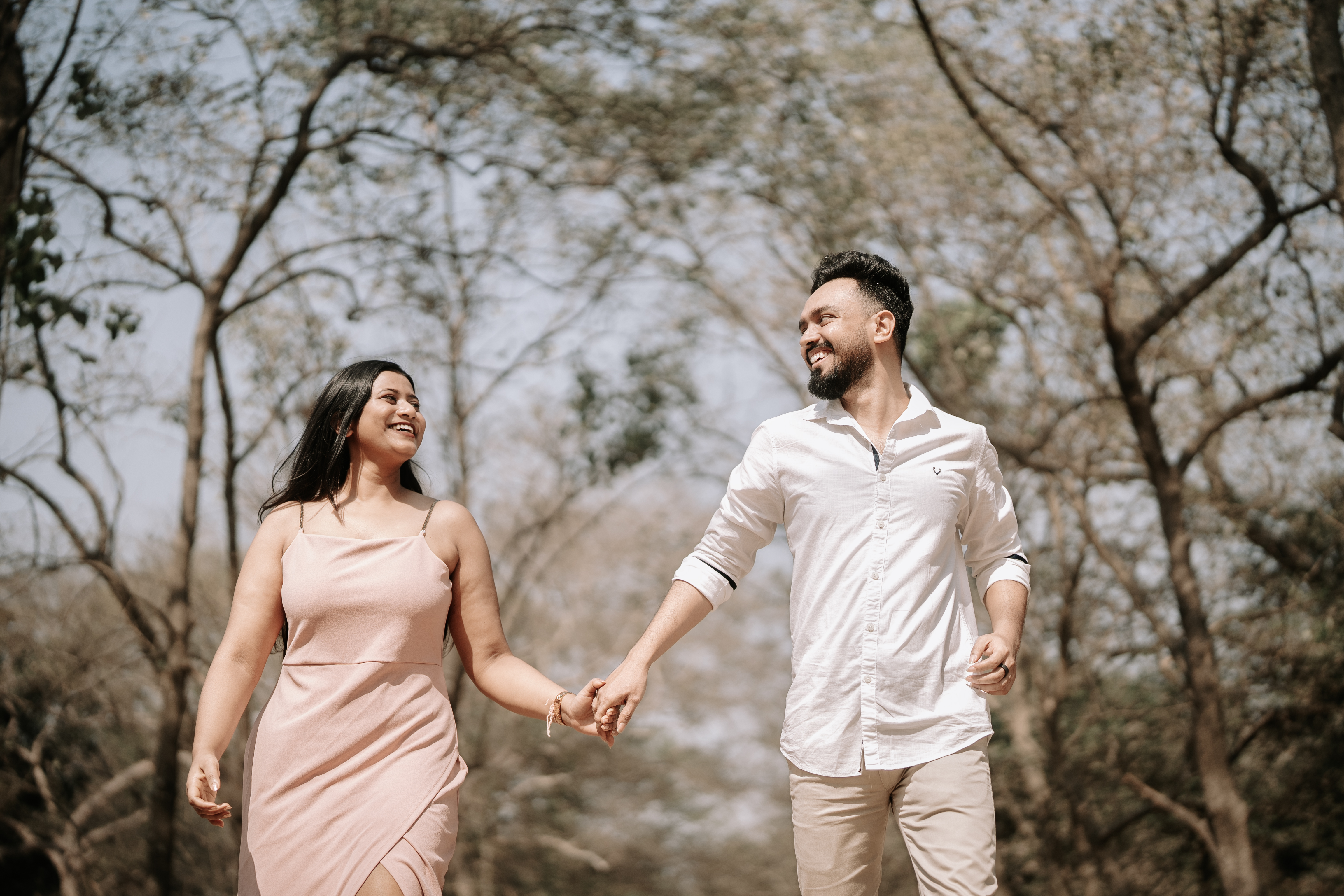 Rituparna and Shoumo walking through a sunlit park, laughing together