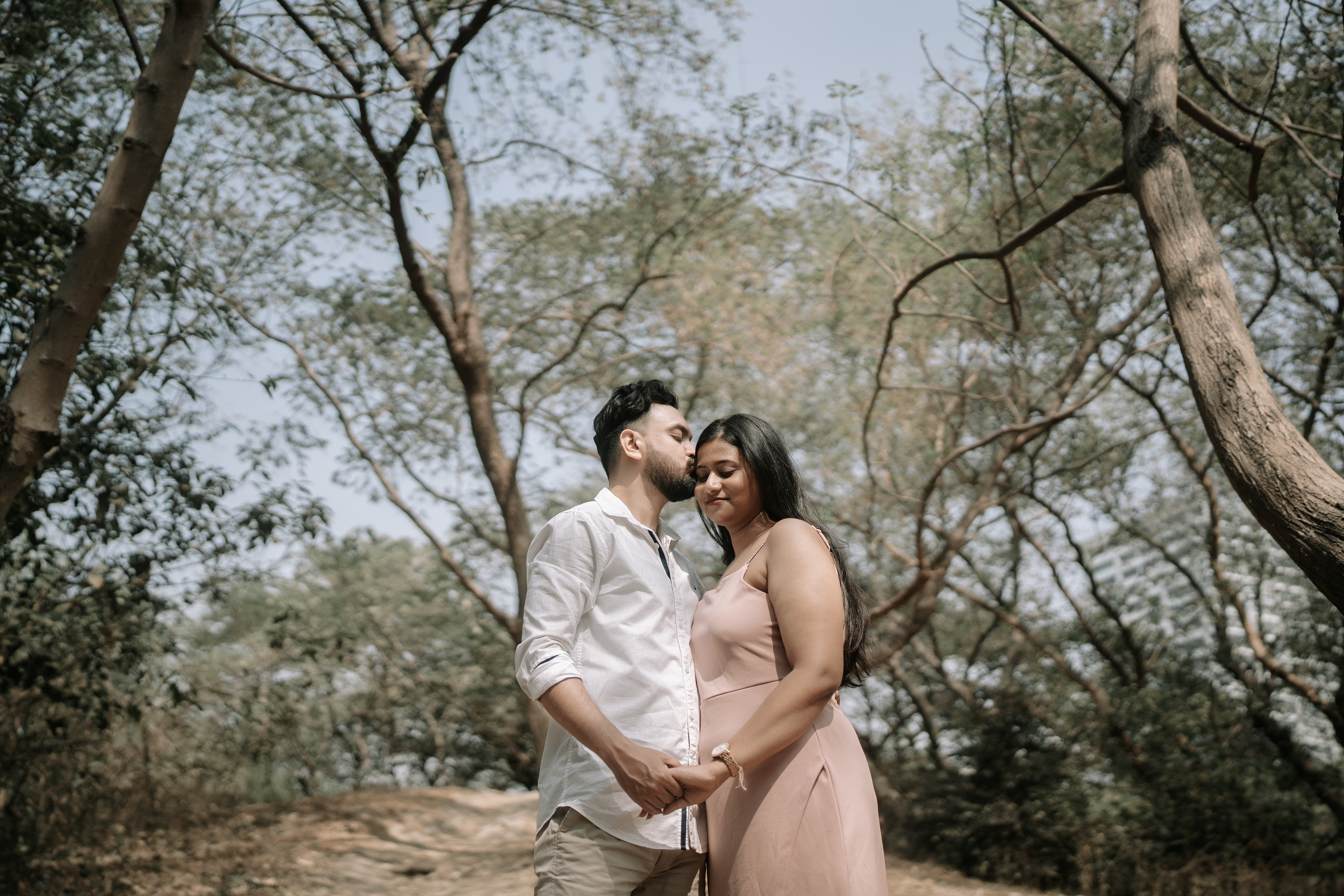 Rituparna and Shoumo sharing a nose kiss in the park surrounded by greenery