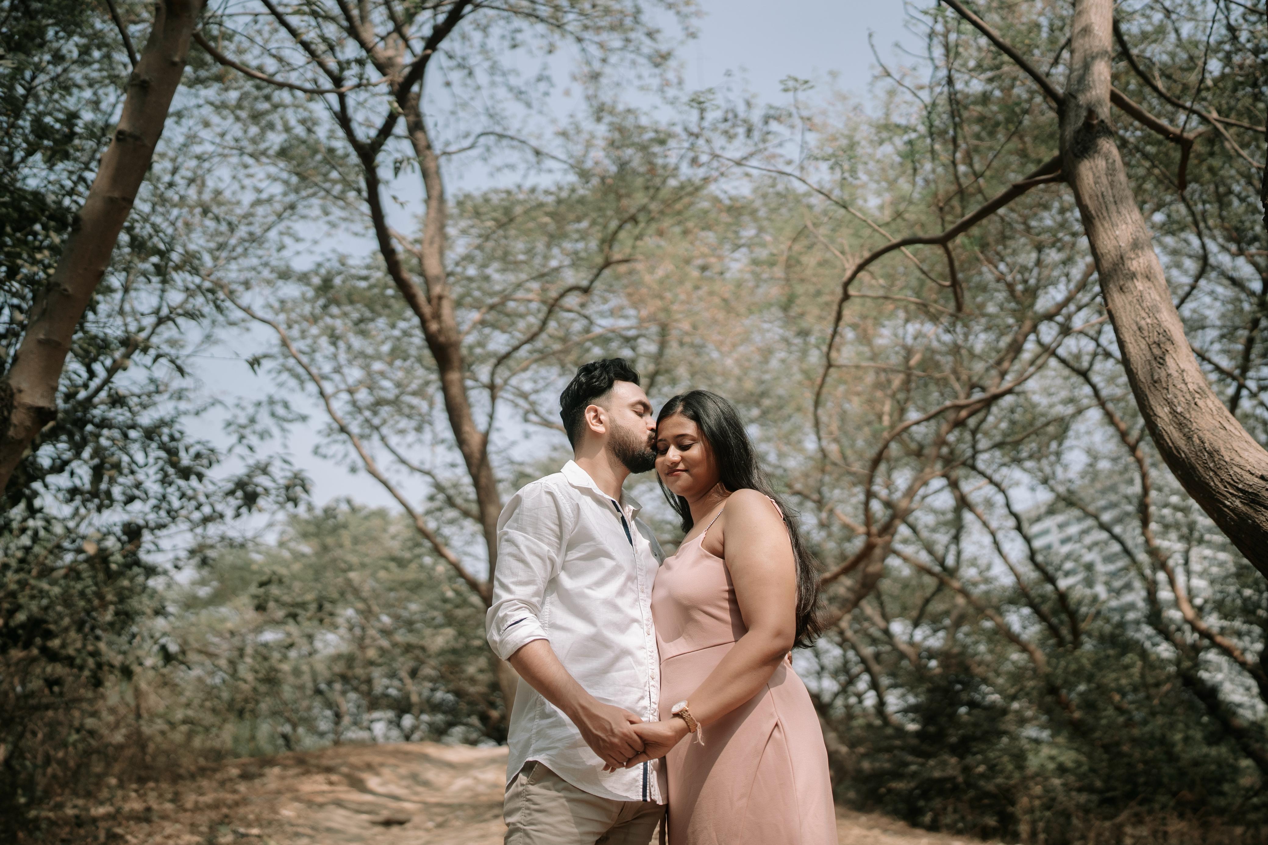 Shoumo kissing Rituparna's forehead tenderly among the trees