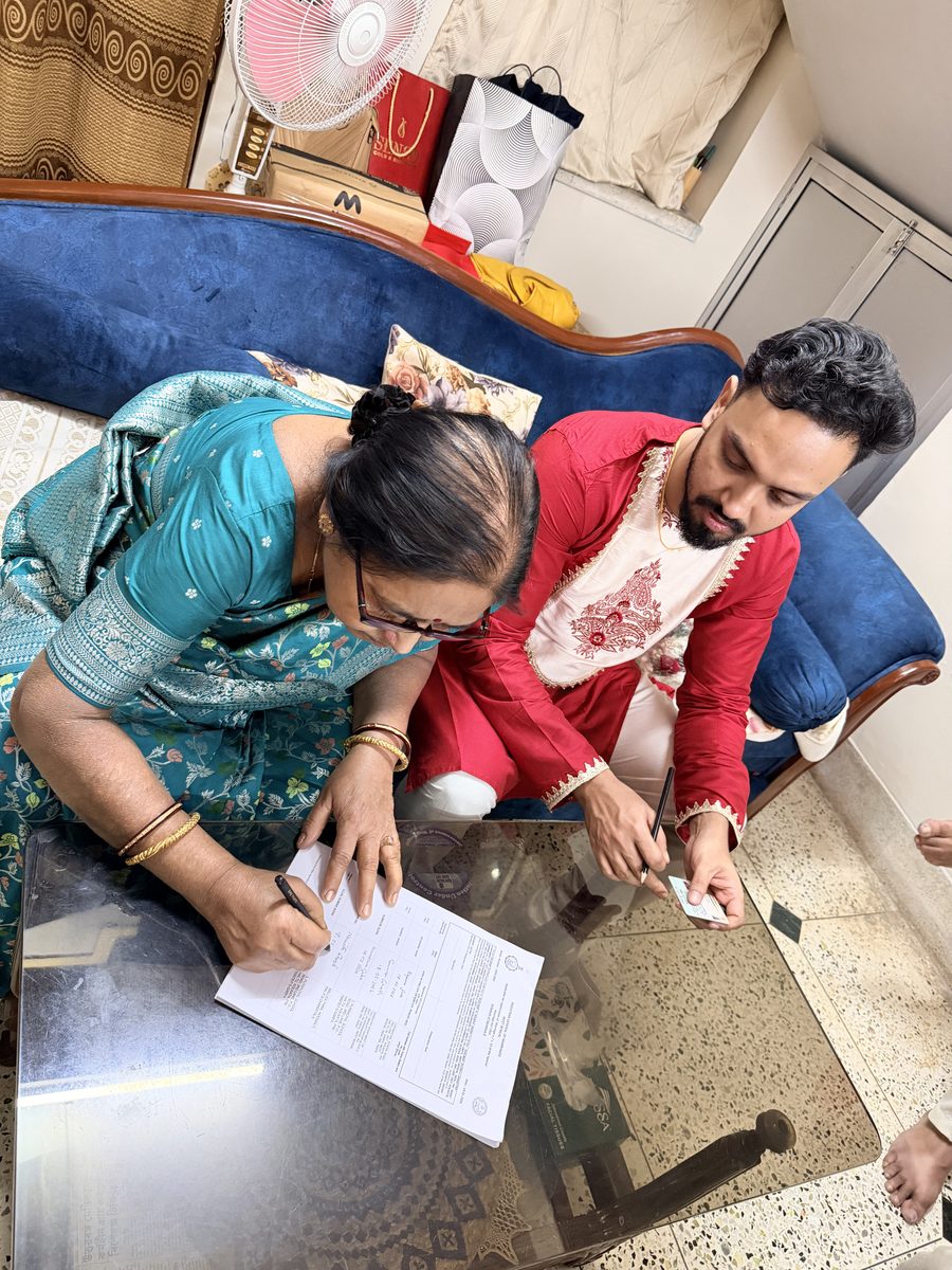 Overhead shot of Rituparna and Shoumo signing documents on the bed