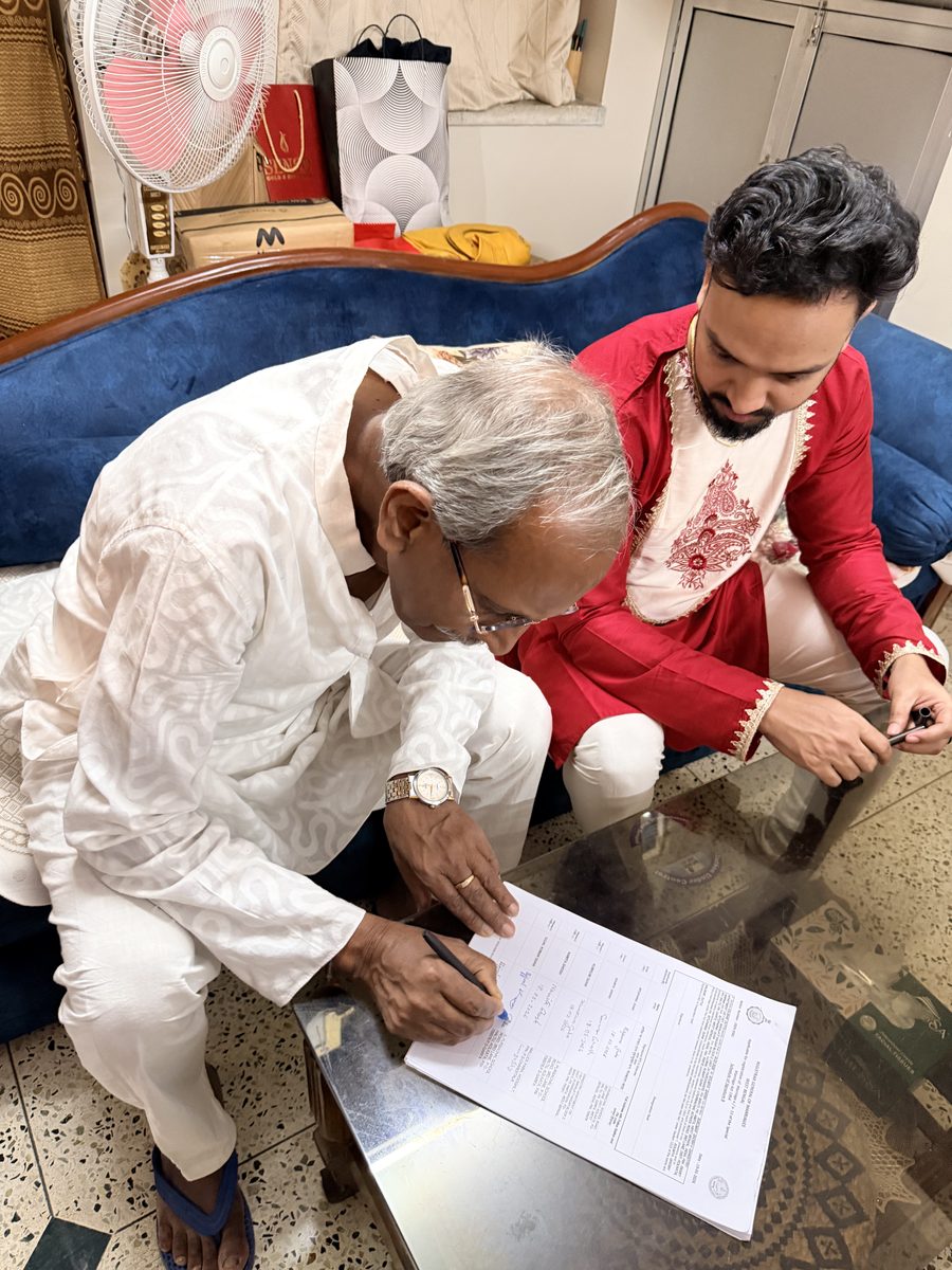 Elder man in white and Shoumo signing marriage documents on the floor