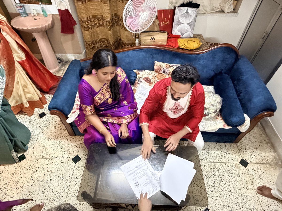 Rituparna and Shoumo reviewing documents together on the blue couch