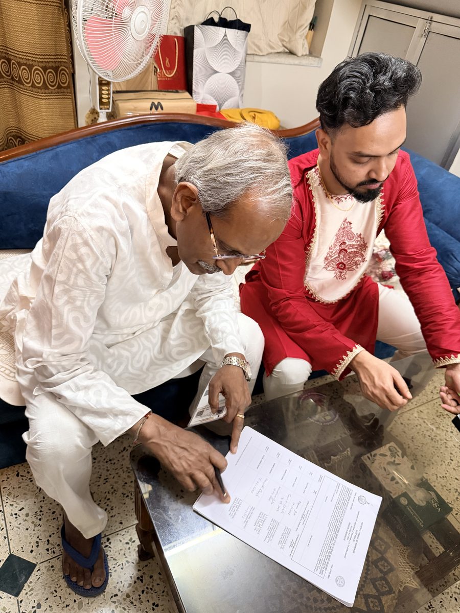Elder man in white reviewing ceremony papers with Shoumo